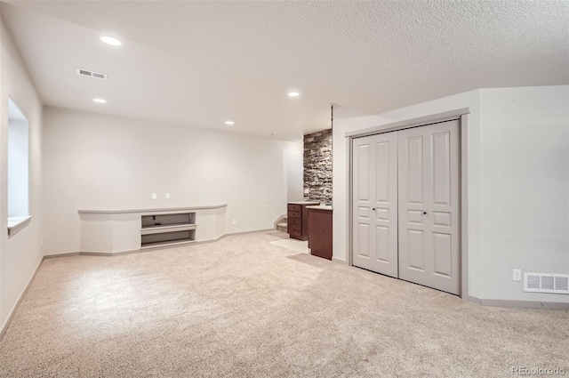 interior space featuring a textured ceiling and light colored carpet