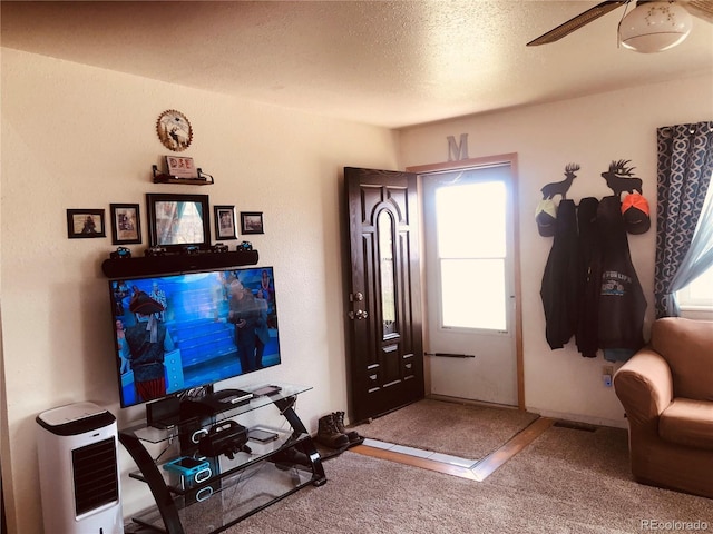 foyer entrance with plenty of natural light, carpet, ceiling fan, and a textured ceiling