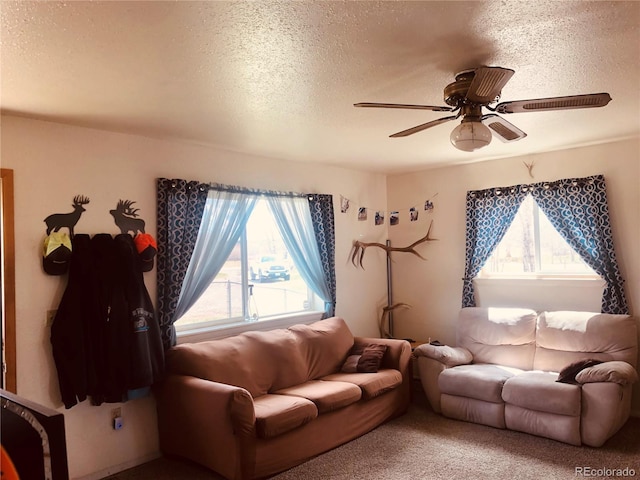 carpeted living area with a textured ceiling and ceiling fan