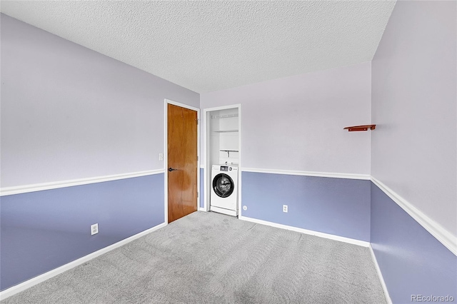 carpeted spare room with baseboards, stacked washing maching and dryer, and a textured ceiling