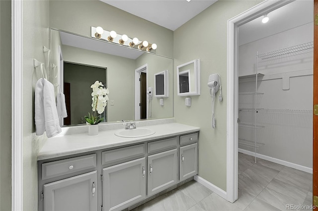 bathroom with baseboards, vanity, and a spacious closet