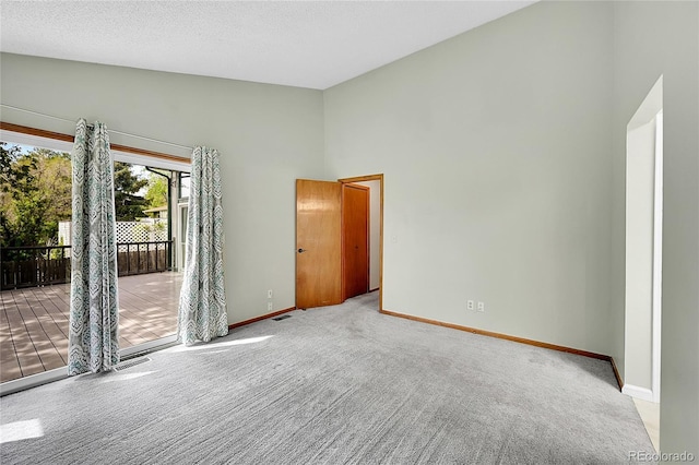 carpeted spare room featuring baseboards, high vaulted ceiling, and visible vents
