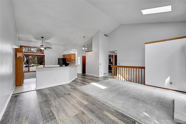 unfurnished living room with a ceiling fan, baseboards, visible vents, high vaulted ceiling, and wood finished floors