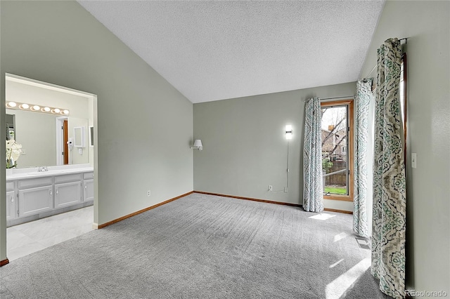 unfurnished bedroom with vaulted ceiling, a textured ceiling, a sink, and baseboards