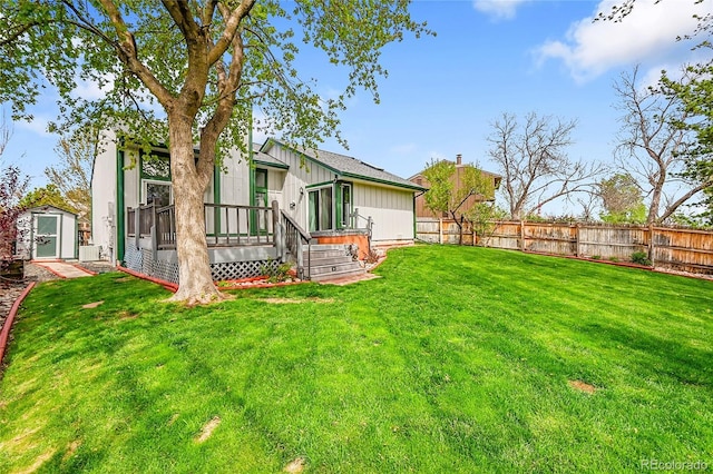 rear view of property featuring a yard, an outdoor structure, a storage shed, and fence