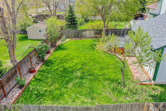 view of yard featuring an outbuilding, a fenced backyard, and a storage unit