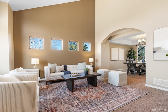 carpeted living room featuring a high ceiling and a notable chandelier