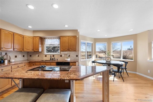 kitchen with tasteful backsplash, a kitchen island, black appliances, sink, and a kitchen breakfast bar