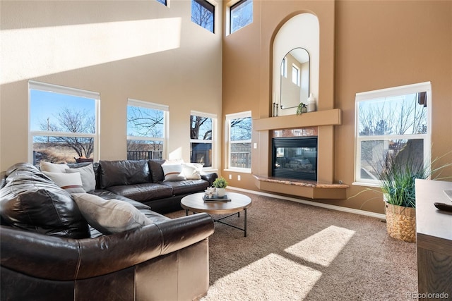 living room featuring carpet flooring, a towering ceiling, and plenty of natural light