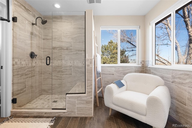 bathroom with tile walls, hardwood / wood-style floors, and a shower with door