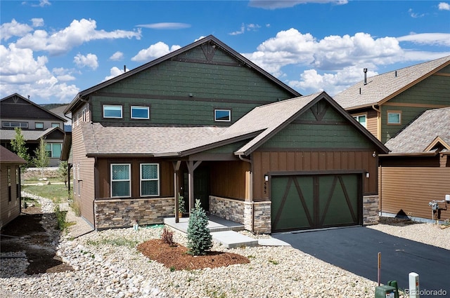craftsman house with a garage, stone siding, aphalt driveway, and board and batten siding