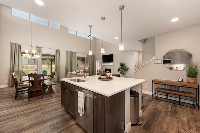 kitchen featuring stainless steel appliances, a sink, open floor plan, dark brown cabinetry, and a lit fireplace