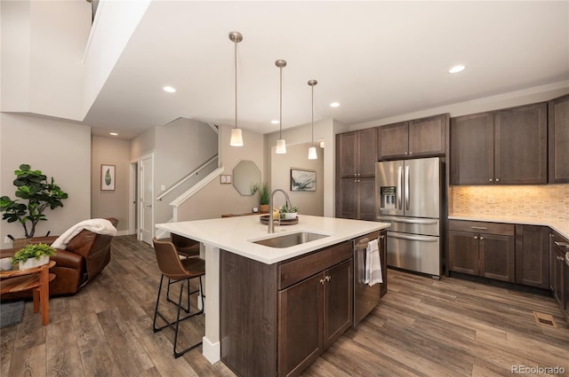 kitchen with dark wood-type flooring, dark brown cabinetry, stainless steel appliances, and a sink