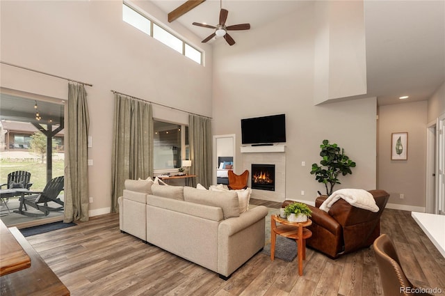 living room featuring a fireplace with flush hearth, ceiling fan, baseboards, and wood finished floors