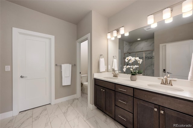 bathroom featuring marble finish floor, toilet, a stall shower, and a sink