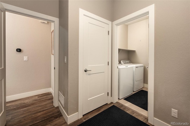 clothes washing area with dark wood-type flooring and separate washer and dryer