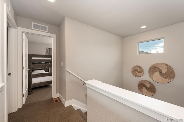 hall with an upstairs landing, dark carpet, baseboards, visible vents, and recessed lighting