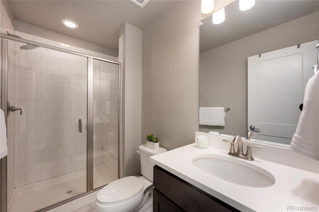 bathroom with toilet, vanity, and a stall shower
