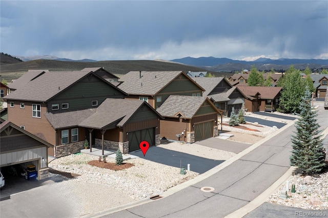 exterior space with a residential view, a mountain view, stone siding, a garage, and a shingled roof