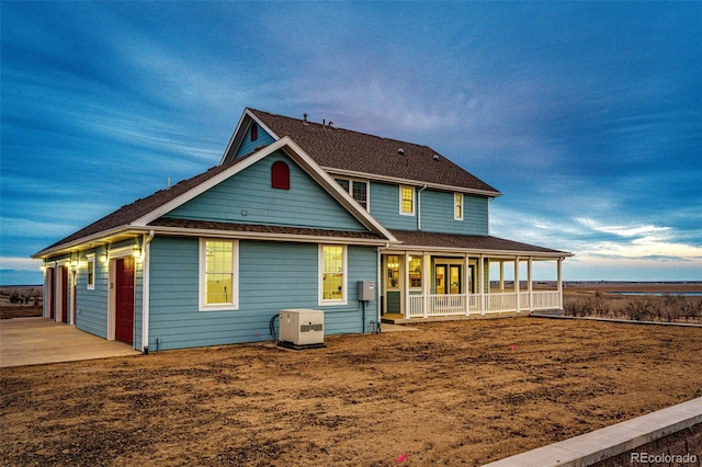 rear view of house featuring a porch and a shingled roof