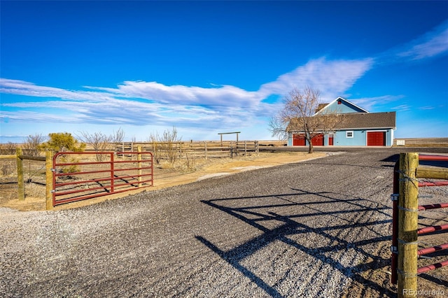 view of street featuring a rural view, driveway, and a gated entry