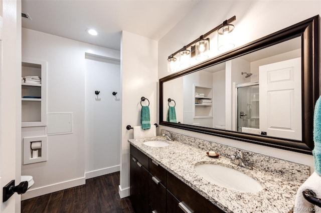 bathroom featuring wood finished floors, a stall shower, a sink, and baseboards