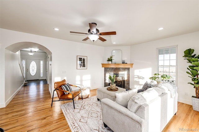 living room featuring arched walkways, light wood-type flooring, baseboards, and recessed lighting