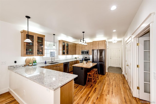 kitchen featuring light wood-style floors, a kitchen bar, appliances with stainless steel finishes, and a sink