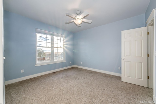 carpeted empty room with baseboards, visible vents, and a ceiling fan