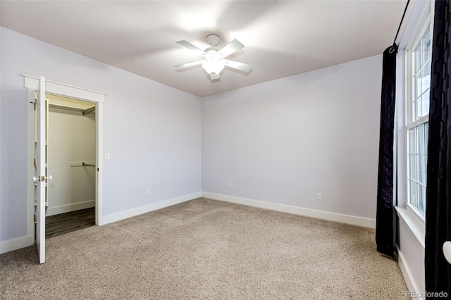 unfurnished bedroom with a spacious closet, a ceiling fan, and baseboards