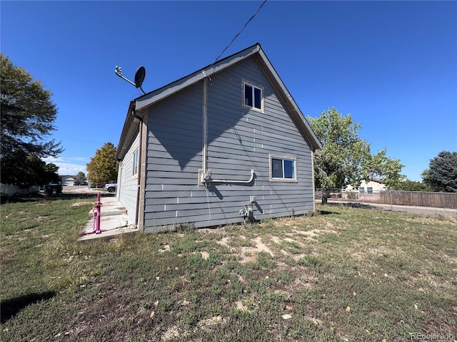 view of home's exterior with fence and a lawn