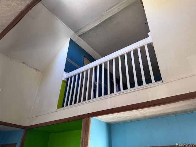 stairs featuring a textured ceiling and vaulted ceiling