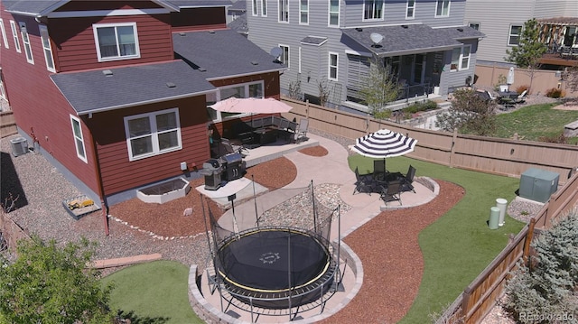 back of house with a shingled roof, a fenced backyard, a patio area, and an outdoor fire pit