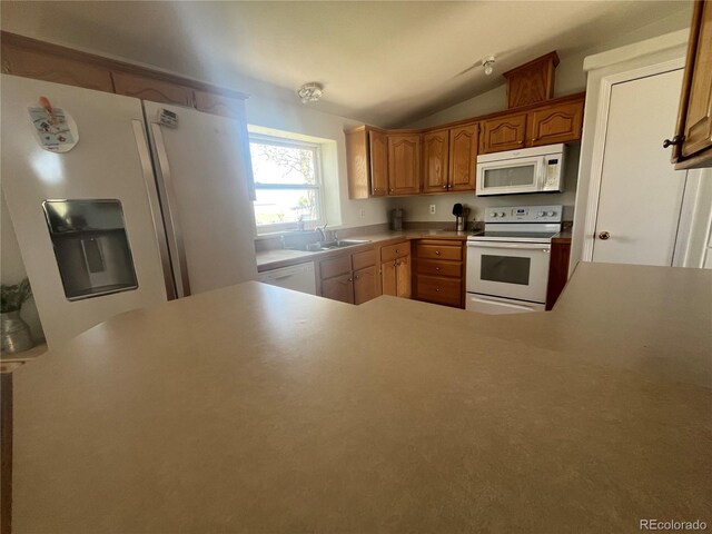 235 Marion St, Burlington, CO 80807 - kitchen with white appliances, a sink, vaulted ceiling, light countertops, and a peninsula