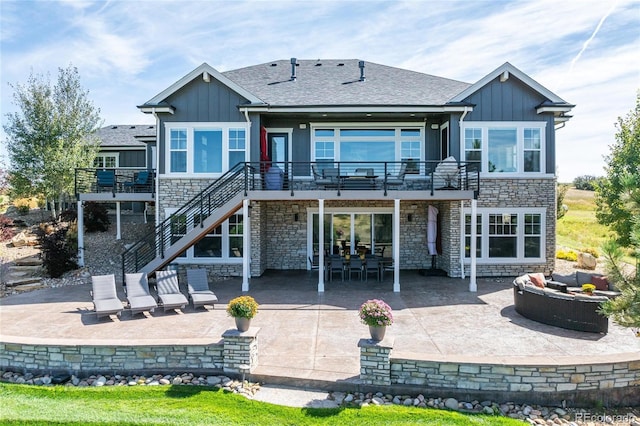9563 Red Primrose St, Franktown, CO 80116 - rear view of house featuring stone siding, an outdoor living space with a fire pit, board and batten siding, a patio, and a wooden deck