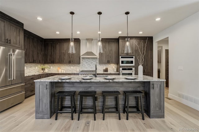 16510 Early Light Dr, Colorado Springs, CO 80908 - kitchen featuring visible vents, wall chimney exhaust hood, tasteful backsplash, and high quality fridge
