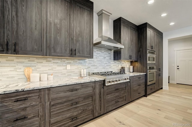 16510 Early Light Dr, Colorado Springs, CO 80908 - kitchen with light wood-style floors, decorative backsplash, wall chimney exhaust hood, and appliances with stainless steel finishes