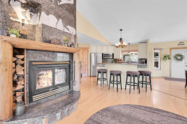 10786 Marclif Rd, Conifer, CO 80433 - living room featuring a chandelier, light wood-style floors, a fireplace, and vaulted ceiling