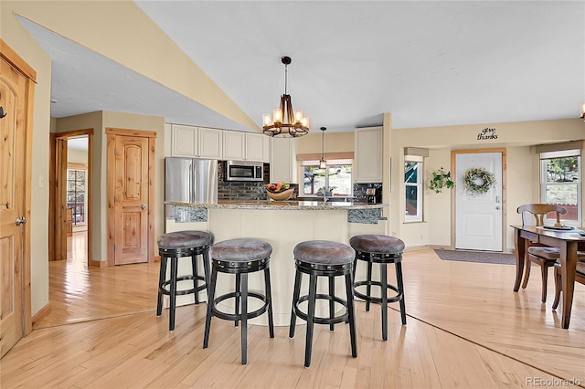 10786 Marclif Rd, Conifer, CO 80433 - kitchen featuring stainless steel appliances, a kitchen breakfast bar, a chandelier, decorative backsplash, and vaulted ceiling