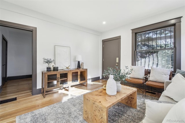 living room with recessed lighting, visible vents, baseboards, and wood finished floors