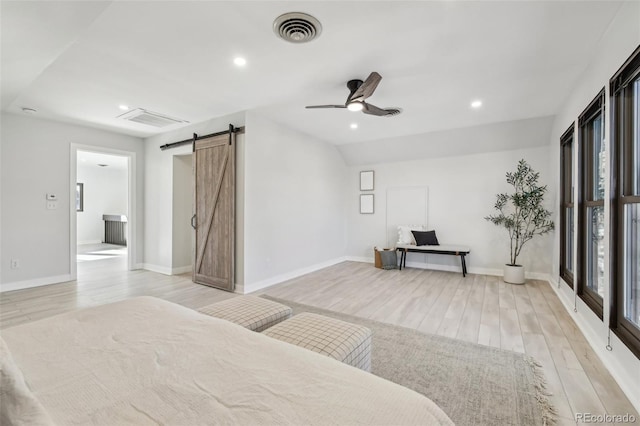 bedroom with visible vents, recessed lighting, a barn door, and light wood-style floors