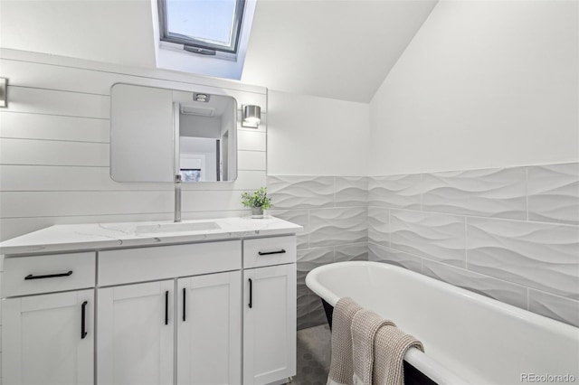 full bathroom featuring a soaking tub, a skylight, vanity, and tile walls