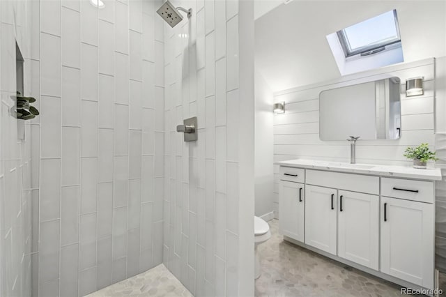 full bath featuring toilet, a skylight, tiled shower, and vanity