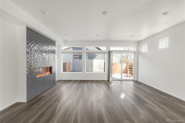 unfurnished living room with baseboards, dark wood-type flooring, and a fireplace