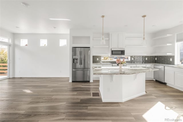 kitchen with decorative backsplash, white cabinets, stainless steel appliances, and open shelves