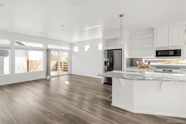 kitchen featuring open shelves, a kitchen breakfast bar, backsplash, wood finished floors, and stainless steel appliances