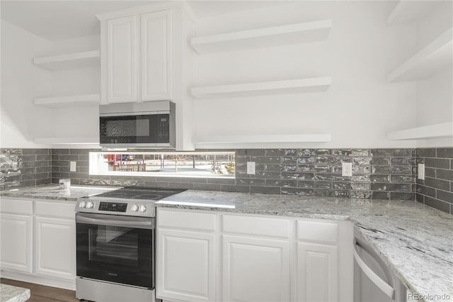 kitchen featuring light stone counters, decorative backsplash, appliances with stainless steel finishes, white cabinetry, and open shelves