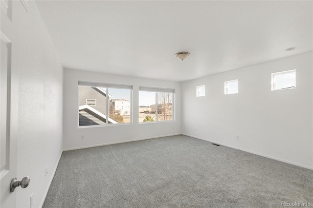 carpeted empty room featuring visible vents and baseboards