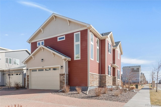 view of side of home featuring decorative driveway and stone siding