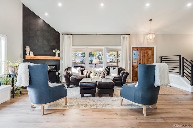 living room with a notable chandelier, high vaulted ceiling, and light wood-type flooring